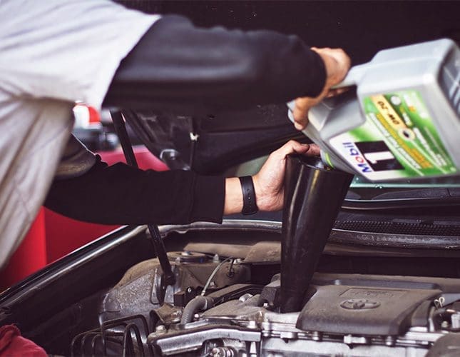 Mechanic pouring mobil oil into car